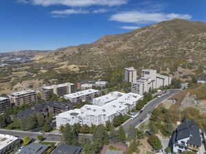 Aerial view of property and surrounding area with a mountainous background and nearby urban area
