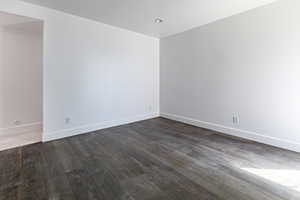 Unfurnished room with baseboards and dark wood-style flooring