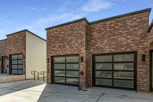 Contemporary home with brick siding, a patio, and stucco siding