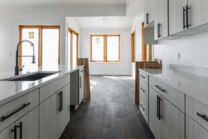 Kitchen with dark wood-type flooring and light stone counters