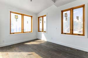 Spare room featuring lofted ceiling and hardwood / wood-style flooring