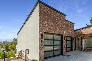 View of home's exterior featuring a garage, brick siding, and driveway