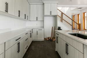 Kitchen with dark wood-style floors, light stone counters, and light brown cabinetry