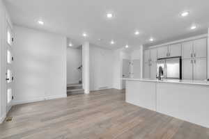 Unfurnished living room featuring stairs, recessed lighting, and light wood-style floors