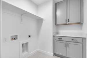 Washroom featuring light tile patterned floors, cabinet space, washer hookup, and electric dryer hookup