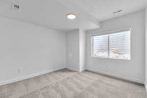 Empty room with light colored carpet and baseboards