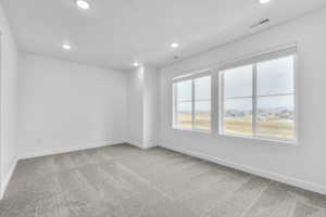 Empty room with light carpet, a residential view, and recessed lighting