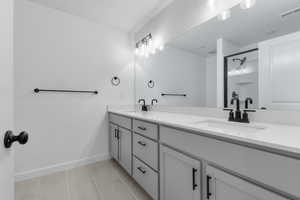 Full bathroom with double vanity, light tile patterned floors, and an enclosed shower