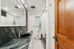 Bathroom with decorative backsplash, vanity, light tile patterned floors, a shower with shower curtain, and track lighting