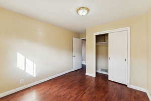 Unfurnished bedroom featuring dark wood-type flooring and a closet