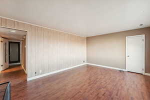 Unfurnished room with dark wood-type flooring and wooden walls