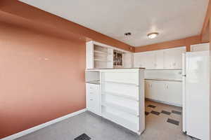 Kitchen with open shelves, white cabinets, and freestanding refrigerator