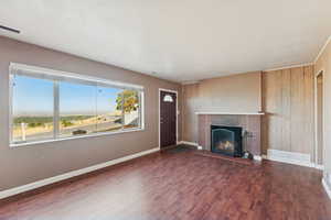 Unfurnished living room with dark wood-type flooring, a fireplace, and wooden walls