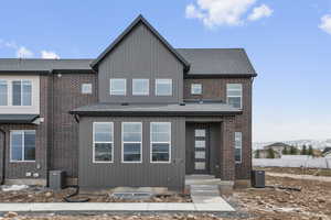 View of front of house with roof with shingles and brick siding