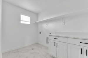 Laundry room featuring light marble finish flooring, washer hookup, cabinet space, and electric dryer hookup