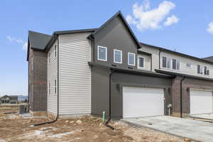 View of property exterior featuring driveway, an attached garage, and brick siding