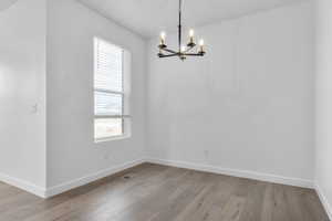 Spare room featuring light wood finished floors and a chandelier