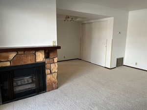 Unfurnished living room featuring light carpet and a fireplace