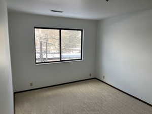 Empty room featuring light carpet and baseboards