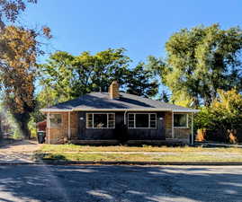View of front facade featuring a chimney, a porch, and a front lawn