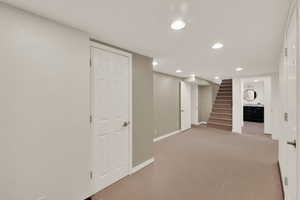 Finished below grade area with recessed lighting, light carpet, and stairs