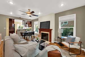 Living area with light wood-type flooring, plenty of natural light, a fireplace with flush hearth, ceiling fan, and recessed lighting