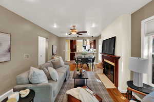 Living room with wood finished floors, a fireplace with flush hearth, recessed lighting, and a ceiling fan