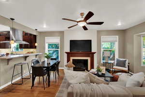 Living room with light wood finished floors, a fireplace, plenty of natural light, a ceiling fan, and recessed lighting