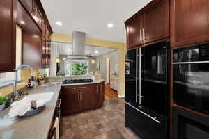 Kitchen with black appliances, dark brown cabinetry, decorative light fixtures, recessed lighting, and stone finish flooring