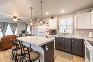 Kitchen featuring a kitchen bar, open floor plan, light countertops, a center island, and pendant lighting