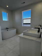 Bathroom featuring double vanity, a soaking tub, light tile patterned floors, and recessed lighting