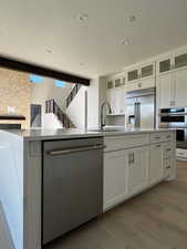 Kitchen featuring white cabinets, JennAir appliances with stainless steel finishes, light stone countertops, light engineered hadwood floors, and a textured ceiling