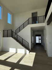 Staircase featuring plenty of natural light, a towering ceiling, light engineered hardwood floors, and recessed lighting