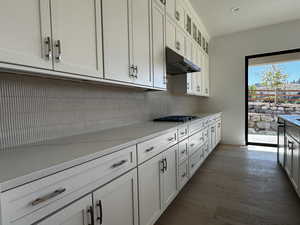 Kitchen featuring white cabinets, glass insert cabinets, and light engineered hardwood floors