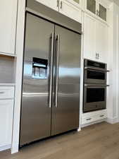 Kitchen featuring JennAir stainless steel appliances, white cabinetry, and light engineered hadwood floors