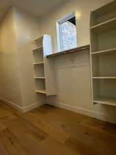 Spacious primary bedroom walk-in closet featuring light engineered hardwood flooring