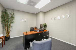 Home office with a drop ceiling and dark carpet