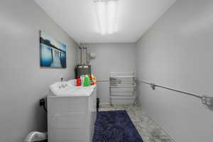 Washroom with a textured ceiling, independent washer and dryer, and water heater