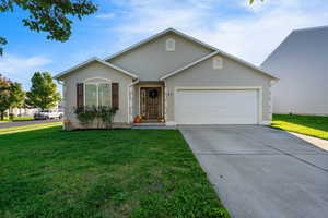 Ranch-style home with stucco siding, a front yard, driveway, and an attached garage