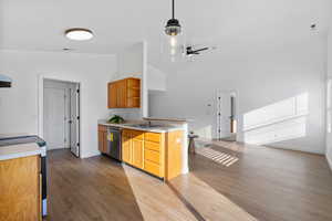 Kitchen with light countertops, open shelves, stainless steel appliances, light wood-type flooring, and lofted ceiling