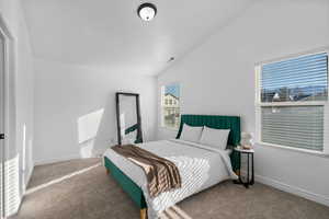 Bedroom with lofted ceiling and carpet floors
