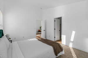 Carpeted bedroom featuring a high ceiling and baseboards