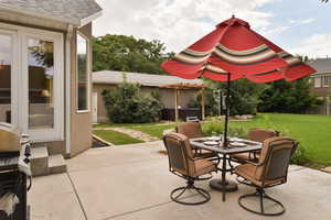 View of patio featuring grilling area, outdoor dining space, and a hot tub