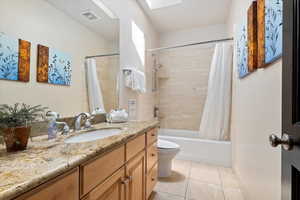 Bathroom with shower / tub combo, vanity, light tile patterned floors, and a skylight