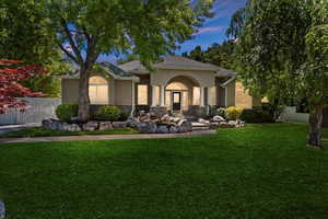 Back of house at dusk with stucco siding and stone siding