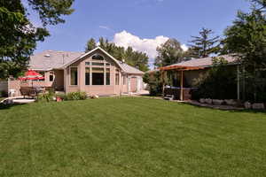 Rear view of property featuring a patio, a yard, a pergola, stucco siding, and a shingled roof