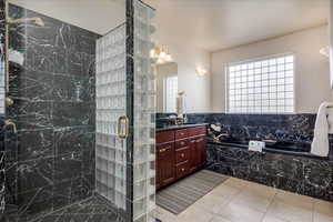 Full bath with a stall shower, a garden tub, vanity, light tile patterned floors, and a chandelier