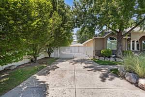 View of side of home featuring stone siding, a gate, and stucco siding