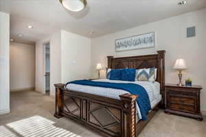 Bedroom with recessed lighting, light colored carpet, and a walk in closet