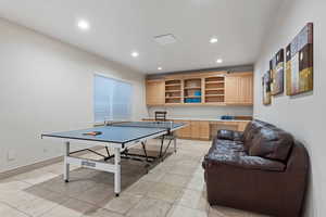 Recreation room with built in study area, recessed lighting, and light tile patterned floors